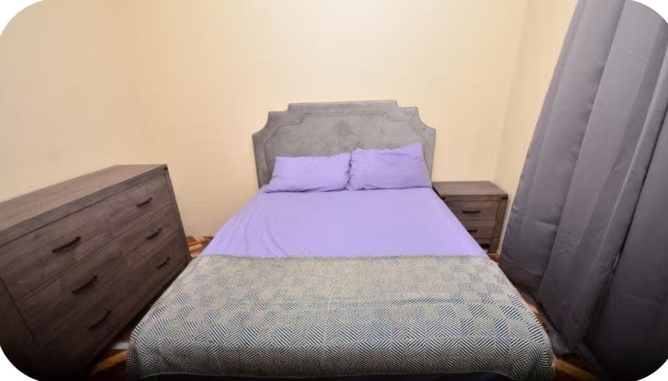 Bedroom with upholstered headboard and purple linens