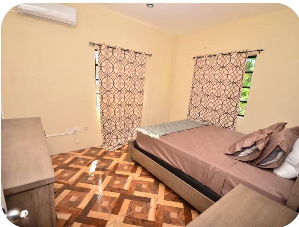 Bedroom with two beds, air conditioning, and patterned curtains