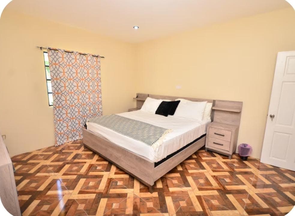 Shared Space - Bedroom with king-size bed and orange accent curtains