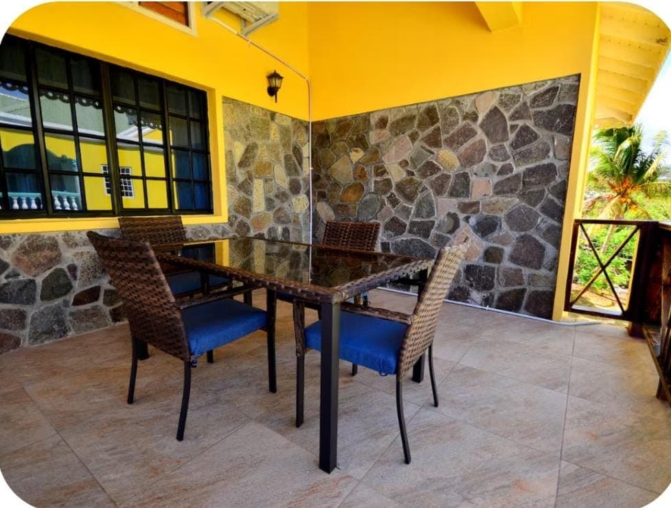 Shared Space - Outdoor patio dining area with stone wall and wicker chairs